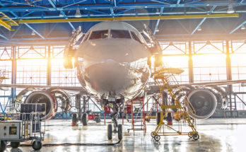 Civil airplane jet on maintenance of engine and fuselage check repair in airport hangar. Bright light at the gate