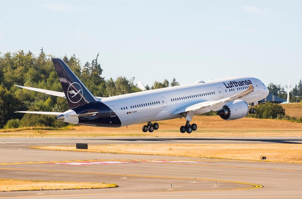 a commercial airliner with wheels down above a runway